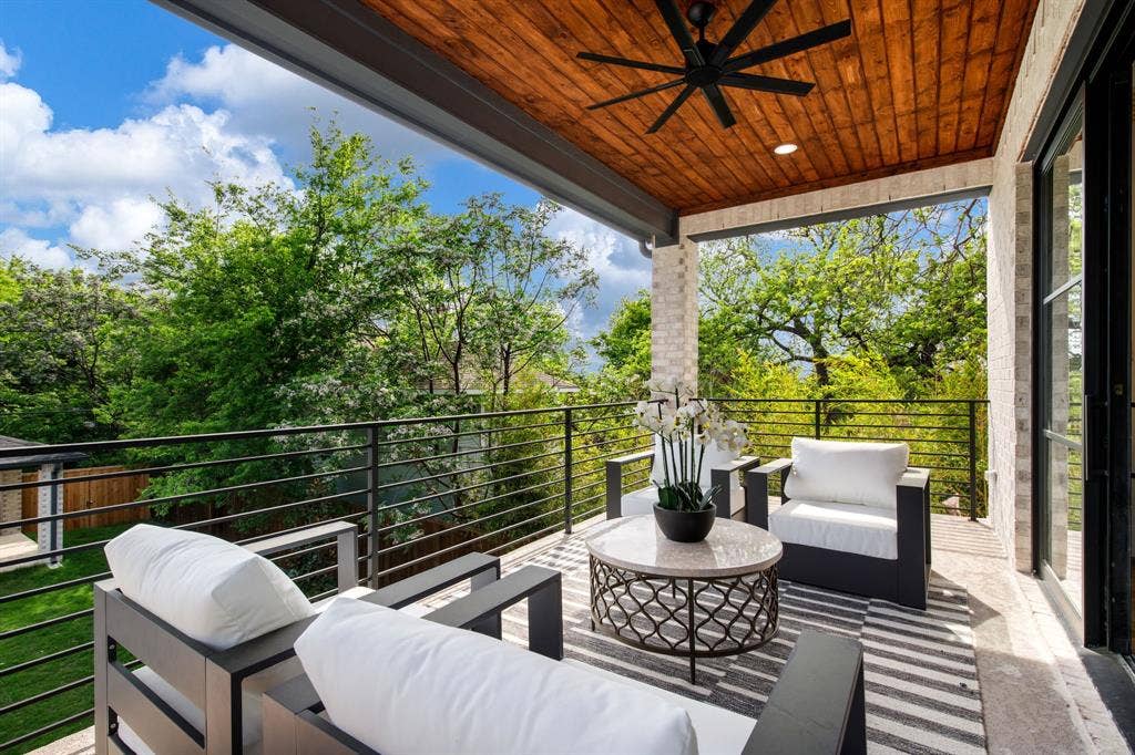 Covered outdoor balcony featuring a wood-finish ceiling, ceiling fan, and stone pillars