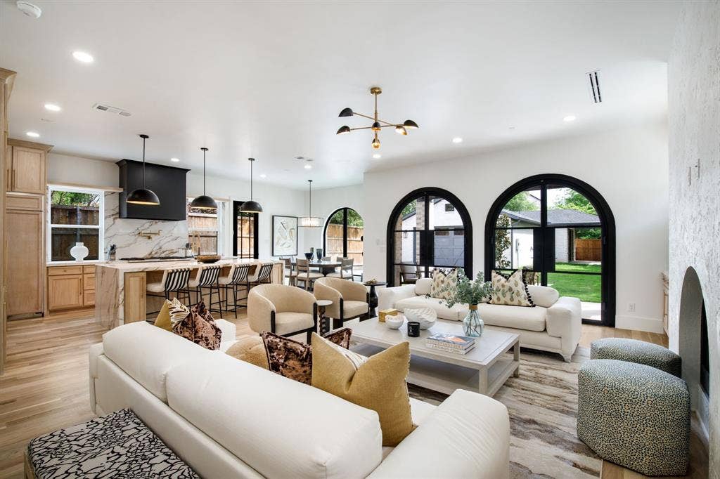 Open-concept living space with light wood-finish flooring, arched windows, and a built-in fireplace