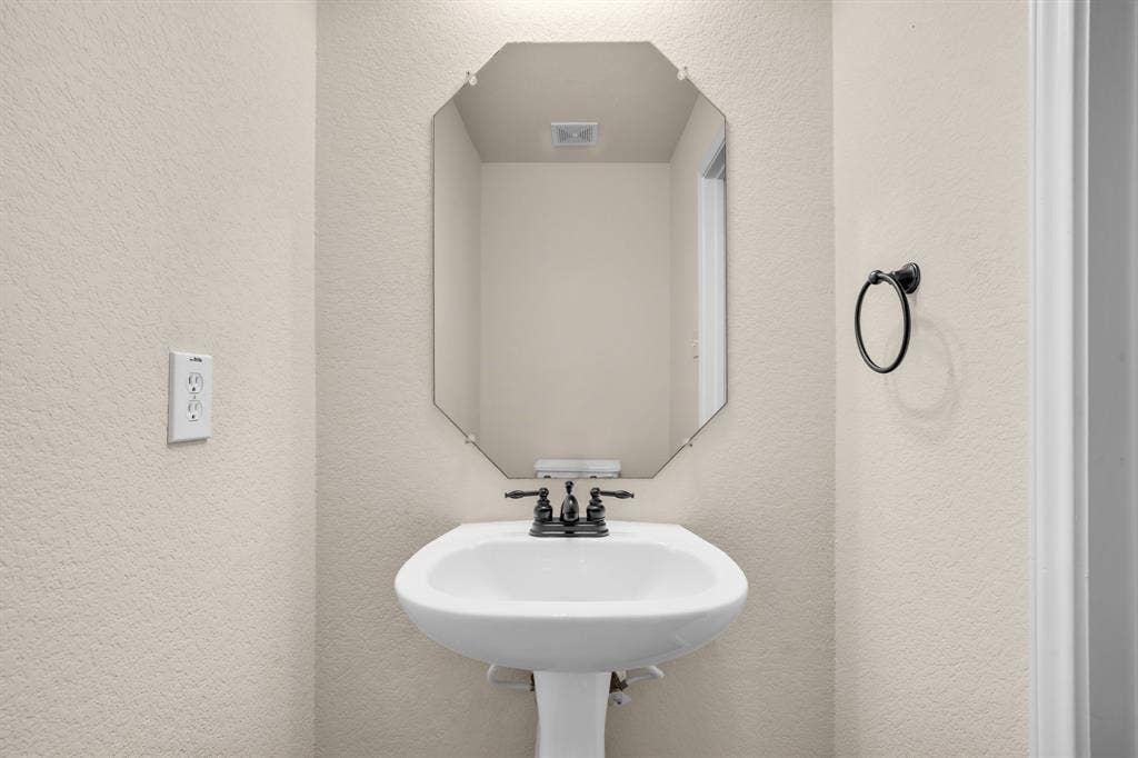 10108 Parker Springs Drive, Waco, TX 76708 Pedestal sink with a matte black faucet, complemented by an octagonal mirror and a round towel ring