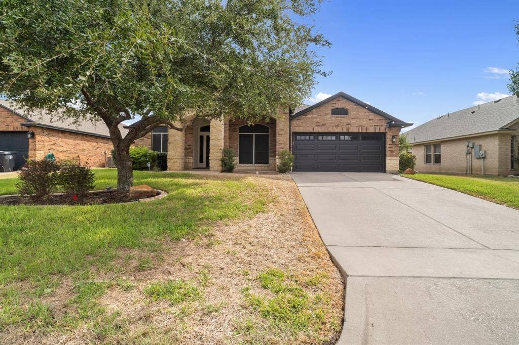 10108 Parker Springs Drive, Waco, TX 76708 Brick and stone exterior with an arched entryway, attached two-car garage, and concrete driveway
