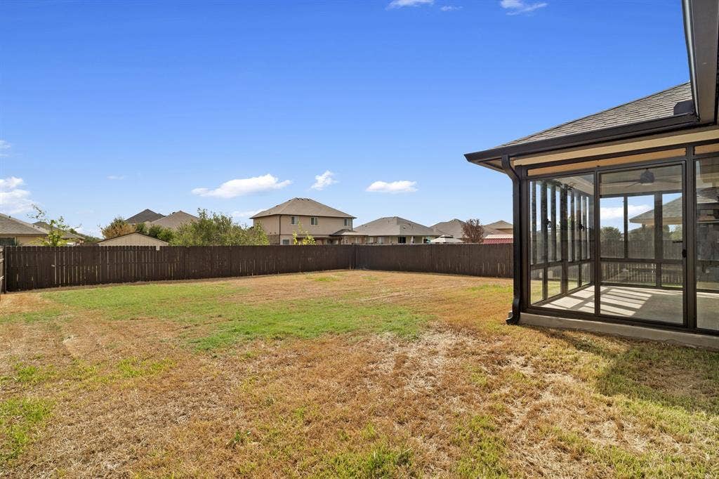 10108 Parker Springs Drive, Waco, TX 76708 Expansive backyard with a full privacy fence and a screened-in patio featuring a ceiling fan