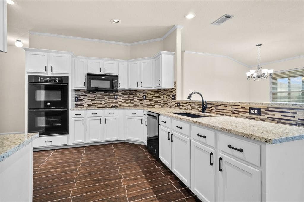 10108 Parker Springs Drive, Waco, TX 76708 Kitchen featuring white shaker-style cabinetry, light-toned countertops, a mosaic tile backsplash, black double wall ovens, and wood-finish flooring