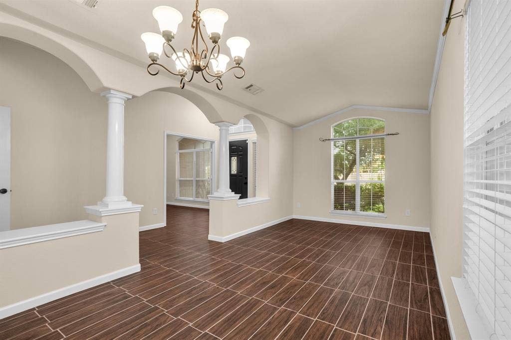 10108 Parker Springs Drive, Waco, TX 76708 Elegant open-concept living space featuring soaring ceilings with decorative crown molding, a brass multi-arm chandelier, and abundant natural light from arched windows