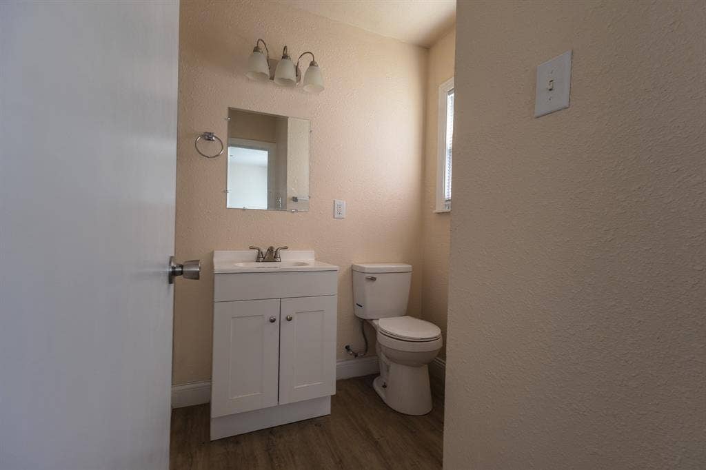 White vanity with cabinet storage, a white ceramic sink, and a chrome faucet