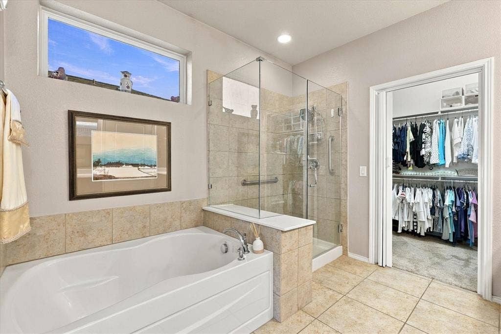1118 Imperial Valley Lane, Frisco, TX 75036 Soaking tub with tile surround, glass-enclosed shower, tiled flooring, and a walk-in closet with built-in shelving