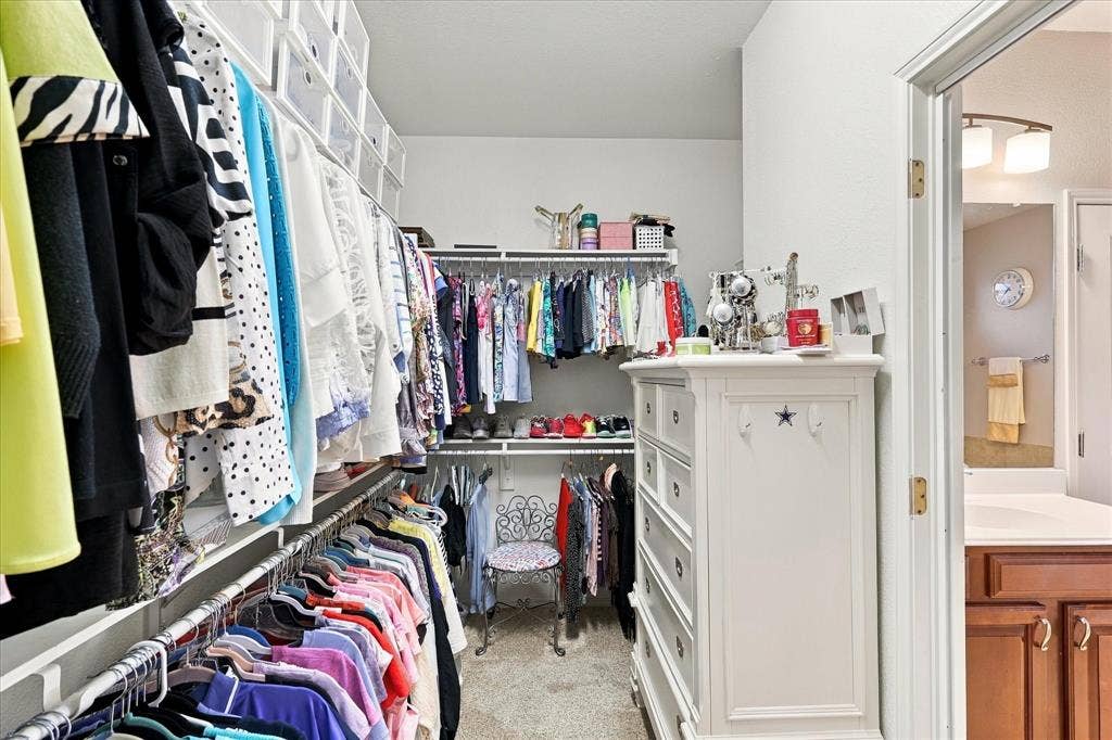 1118 Imperial Valley Lane, Frisco, TX 75036 Walk-in closet featuring extensive built-in shelving, multiple hanging rods, and neutral carpeting