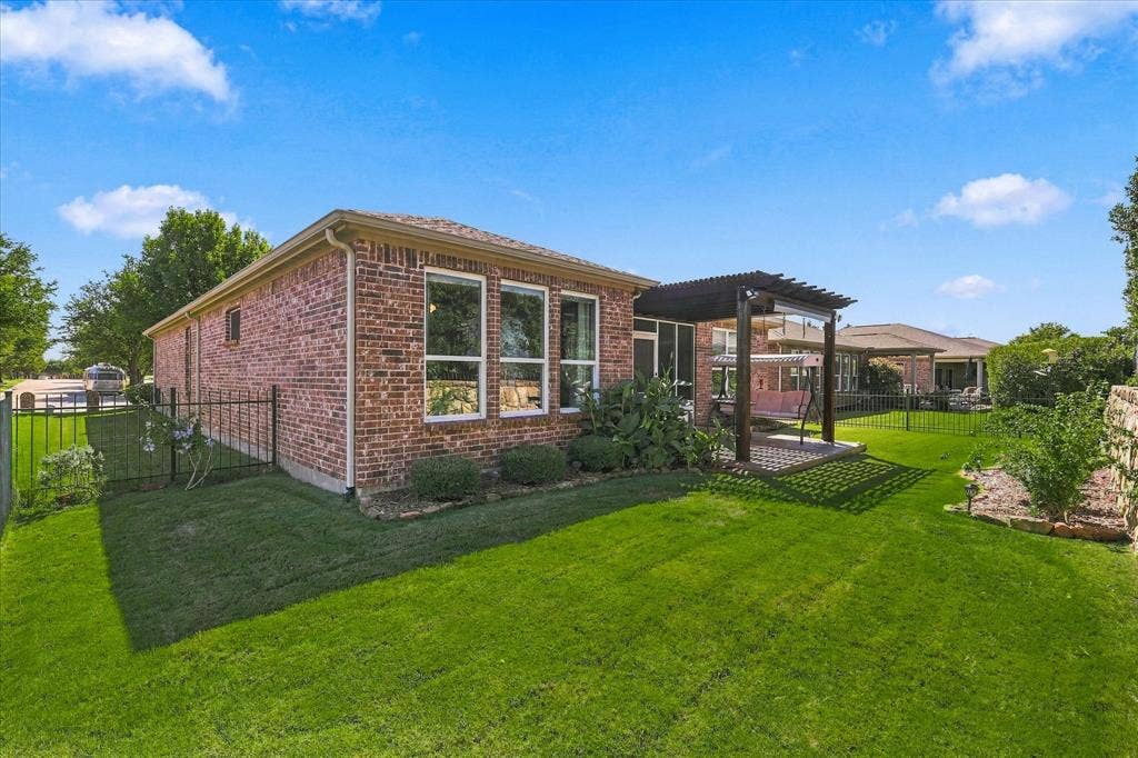 1118 Imperial Valley Lane, Frisco, TX 75036 Brick exterior with multiple windows, leading to a back patio featuring a pergola