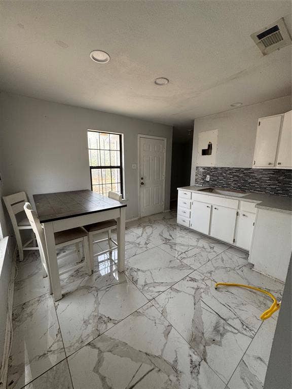415 E 20th Street, Waco, TX 76705 Recessed ceiling lighting, large format tile flooring, white cabinetry, dark countertop, and mosaic tile backsplash