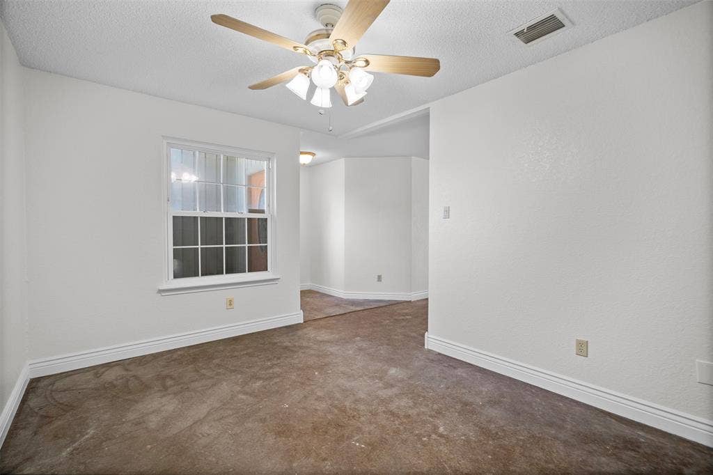 Room featuring a ceiling fan with four wooden-finish blades and a multi-light fixture, single-hung window with a grid pattern, and smooth-finish white walls