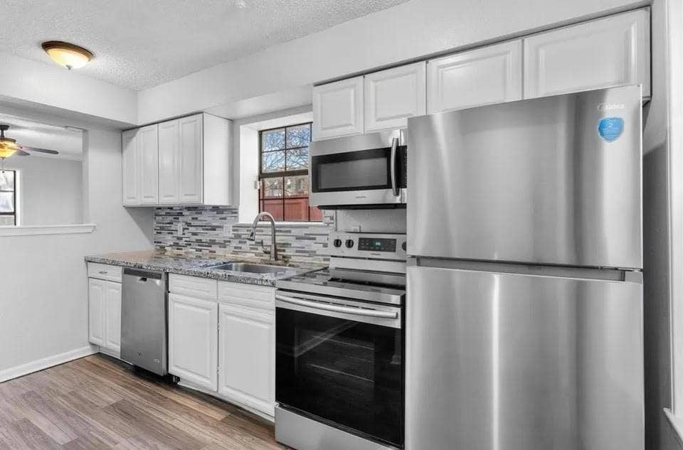 5326 Columbia Avenue, Dallas, TX 75214 Bright kitchen showcasing sleek stainless steel appliances paired with beautiful wood flooring for a cozy, contemporary look.
