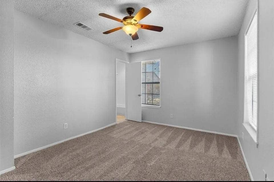 5326 Columbia Avenue, Dallas, TX 75214 A cozy bedroom featuring a neutral-colored carpet, ceiling fan and tall windows, creating a comfortable atmosphere.