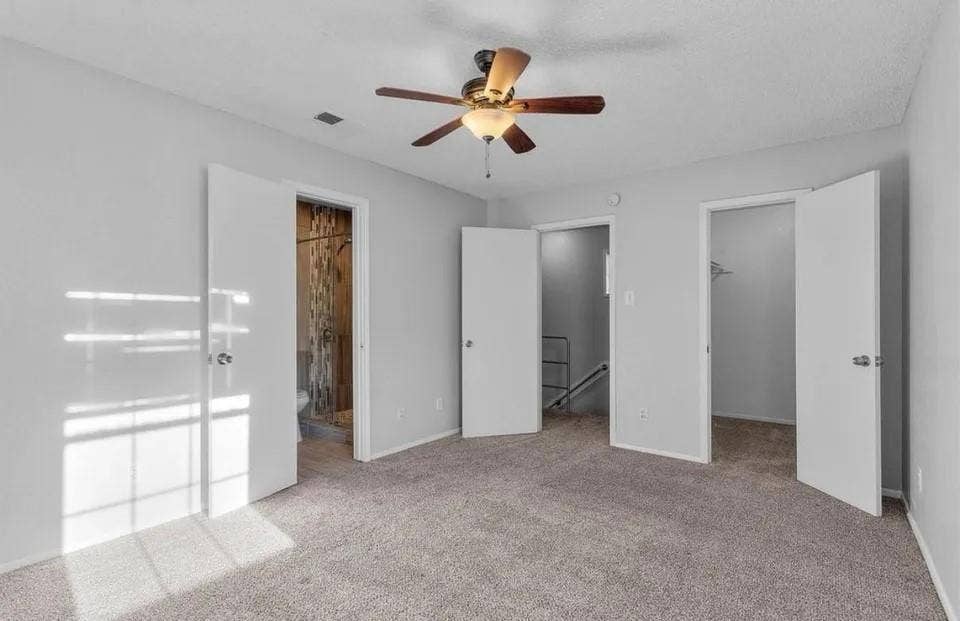 5326 Columbia Avenue, Dallas, TX 75214 A spacious primary bedroom showcasing an en suite bathroom, built-in cabinet, ceiling fan and neutral-colored carpeting, perfect for relaxation and comfort.