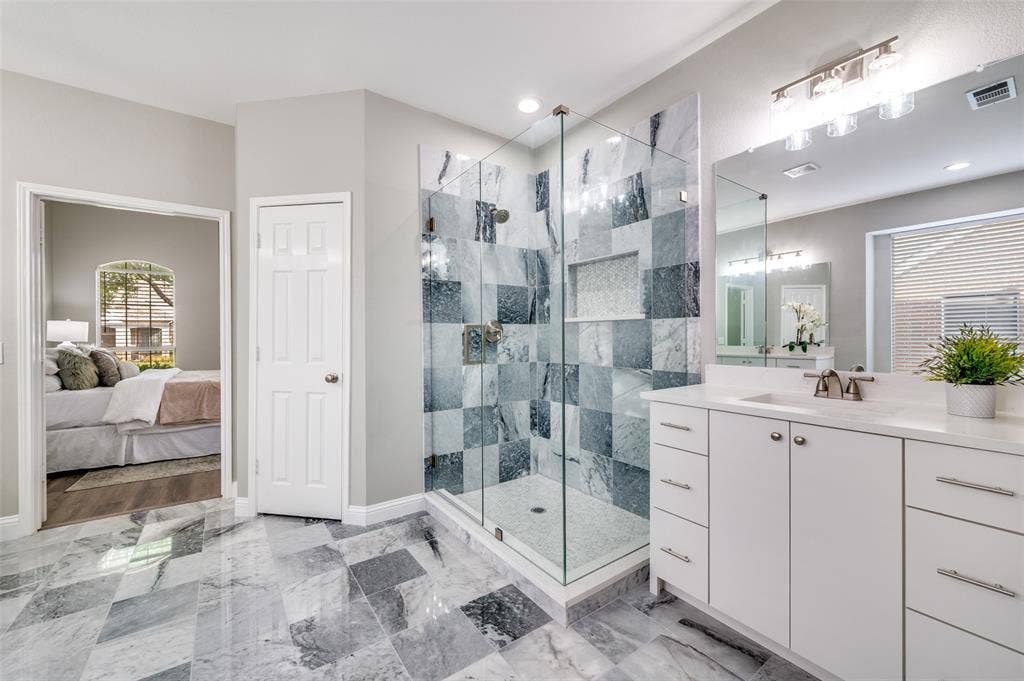 2873 Del Largo Way, Frisco, TX 75033 Glass-enclosed shower with tiled walls and built-in niche, dual basin vanity with white cabinetry, and large format tiled flooring
