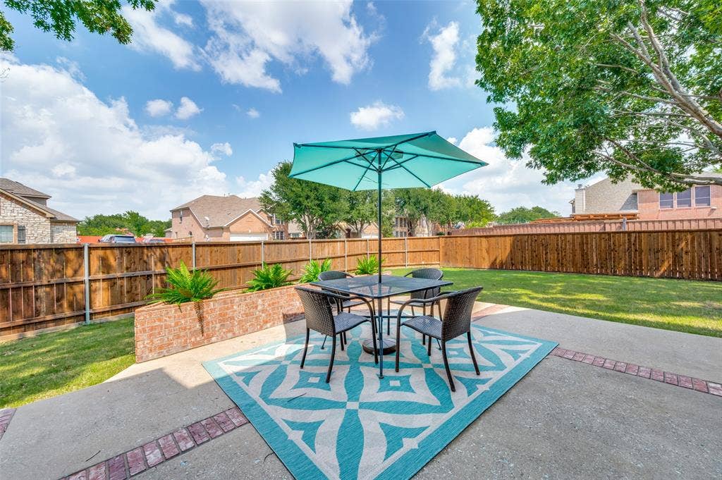 2873 Del Largo Way, Frisco, TX 75033 Expansive backyard featuring a concrete patio with brick accents, a raised brick planter, mature trees, and a privacy fence