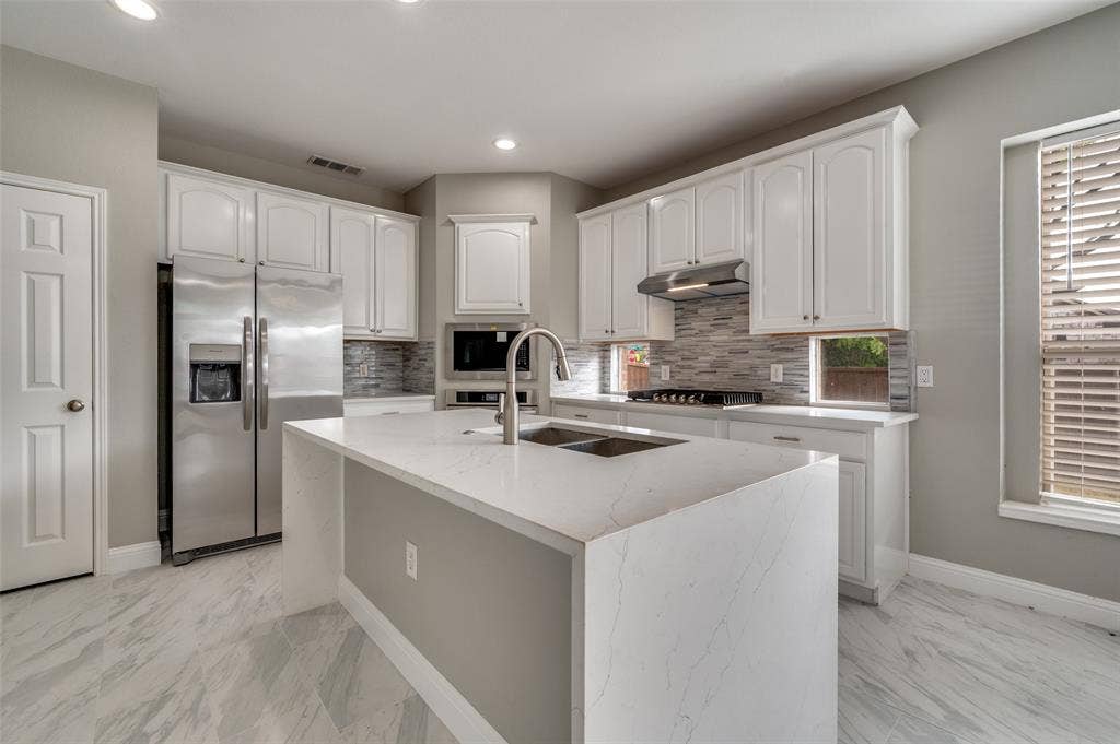 2873 Del Largo Way, Frisco, TX 75033 Kitchen featuring white cabinetry, stainless steel appliances, a center island with a built-in sink, and tile flooring