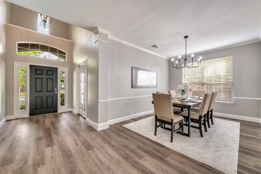 2873 Del Largo Way, Frisco, TX 75033 Wood-finish flooring throughout, two-story foyer with transom window, paneled front door with sidelights, crown molding, and wainscoting