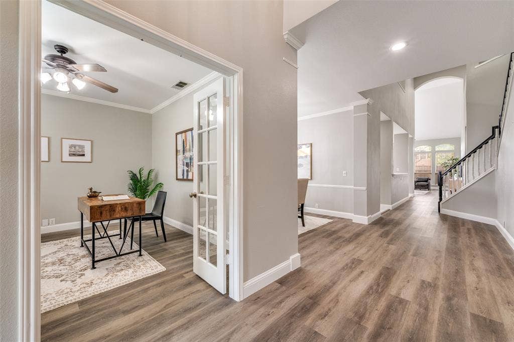 2873 Del Largo Way, Frisco, TX 75033 Welcoming foyer with wood-finish flooring throughout, white French doors with glass panes opening to a dedicated home office, recessed lighting, and a curved staircase with black metal railings