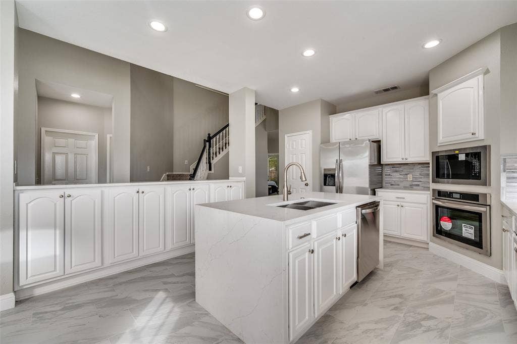 2873 Del Largo Way, Frisco, TX 75033 Kitchen featuring white cabinetry, stainless steel appliances, a center island with sink, and tile flooring