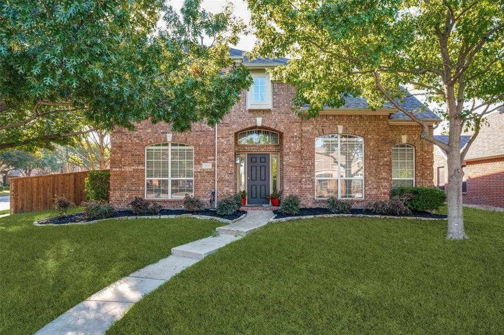 2873 Del Largo Way, Frisco, TX 75033 Brick exterior with arched entryway, manicured lawn, established trees, and a concrete pathway