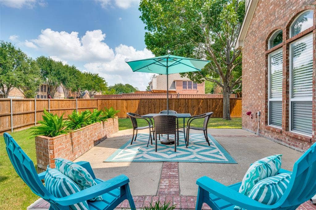 2873 Del Largo Way, Frisco, TX 75033 Expansive concrete patio with brick accents, featuring integrated brick planters, a manicured lawn, and a wood privacy fence