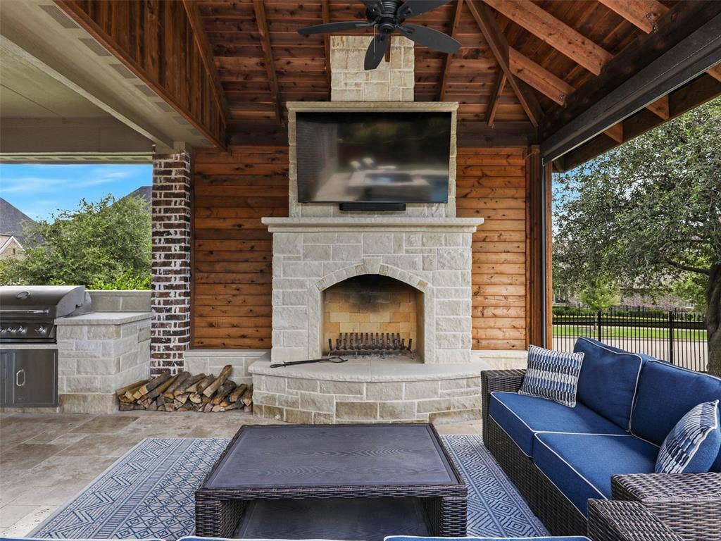 12921 Railhead Court, Frisco, TX 75033 The covered outdoor living center extends the home's entertaining space into the backyard. The roof extension is finished internally with stained cedar, bringing warmth and architectural character overhead. A built-in grilling area and custom fireplace are constructed from 100% Leuders limestone, while the fireplace itself features full masonry construction. Together, these elements create a substantial outdoor gathering space for grilling, dining, relaxing by the fire, or entertaining alongside the pool and spa.