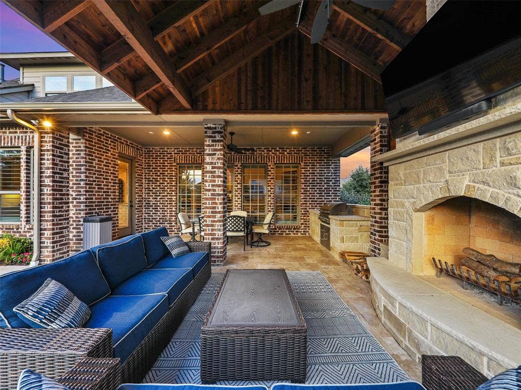 12921 Railhead Court, Frisco, TX 75033 The covered outdoor living center extends the home's entertaining space into the backyard. The roof extension is finished internally with stained cedar, bringing warmth and architectural character overhead. A built-in grilling area and custom fireplace are constructed from 100% Leuders limestone, while the fireplace itself features full masonry construction. Together, these elements create a substantial outdoor gathering space for grilling, dining, relaxing by the fire, or entertaining alongside the pool and spa.