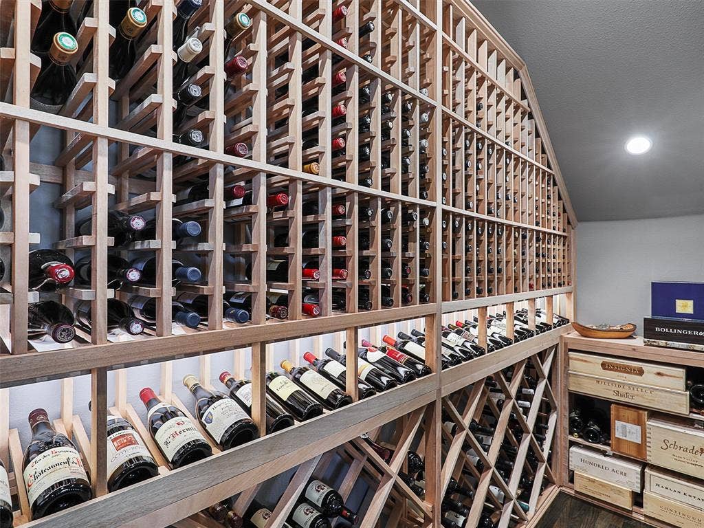12921 Railhead Court, Frisco, TX 75033 One of the home's most distinctive features is its custom wine cellar, completed in 2022 and designed for the serious wine enthusiast. The cellar features a CellarPro 4000S split-system cooling unit engineered to regulate both temperature and humidity. Hard foam insulation within the walls and ceiling, along with moisture-resistant drywall, helps create a controlled environment for the collection. A custom iron entry door with UV-protective glass introduces the space, while custom solid mahogany racking accommodates standard 750ml bottles, larger champagne-style bottles, large-format bottles, and wood cases. Multiple lighting zones with dimmers create an elegant atmosphere, while storage capacity for approximately 800 bottles transforms the cellar into both a functional collection space and a striking architectural feature.