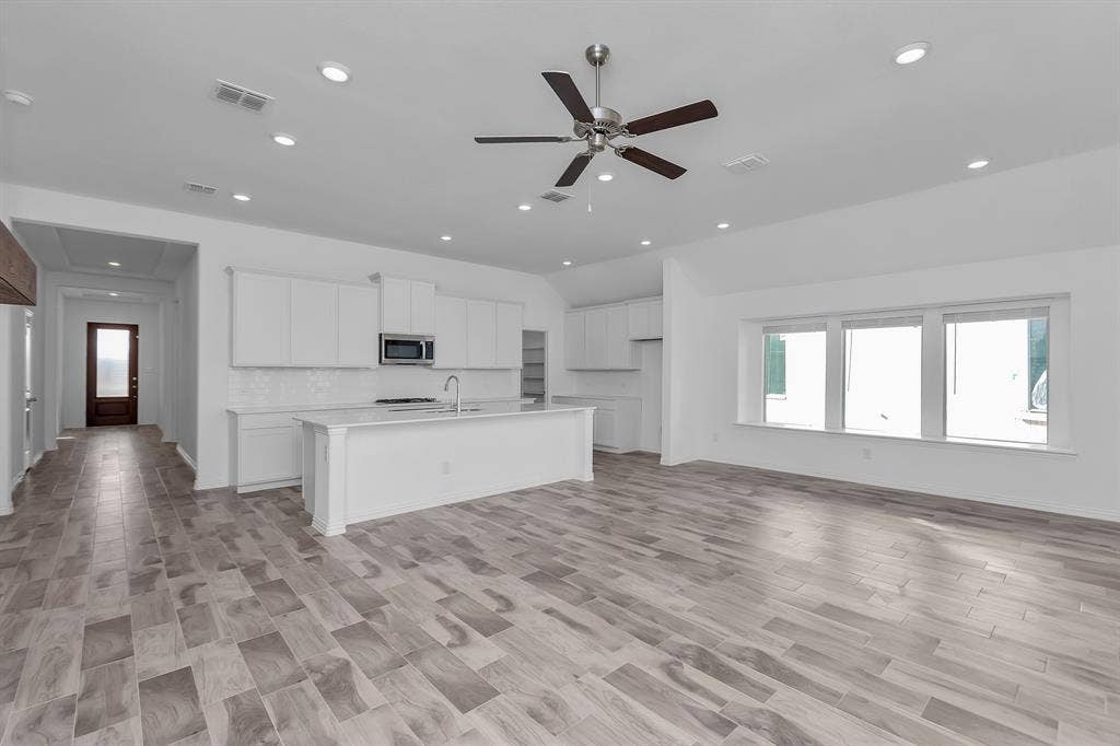 7204 Black Cherry Lane, McKinney, TX 75071 Kitchen featuring stainless steel microwave, lofted ceiling, recessed lighting, a ceiling fan, and an island with sink
