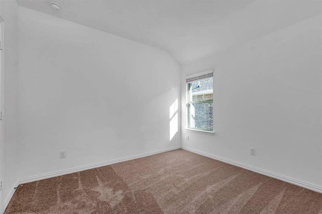 7204 Black Cherry Lane, McKinney, TX 75071 Unfurnished room featuring a smoke detector, vaulted ceiling, and carpet floors