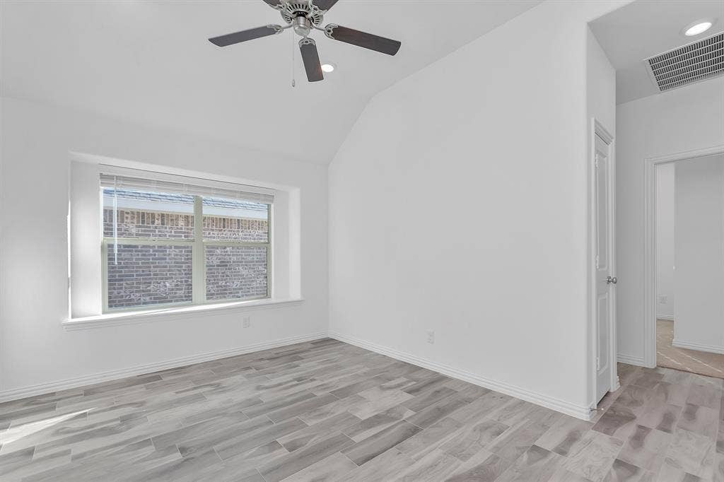 7204 Black Cherry Lane, McKinney, TX 75071 Spare room with light wood-type flooring, vaulted ceiling, and a ceiling fan