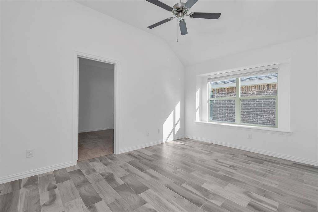 7204 Black Cherry Lane, McKinney, TX 75071 Empty room featuring vaulted ceiling and a ceiling fan
