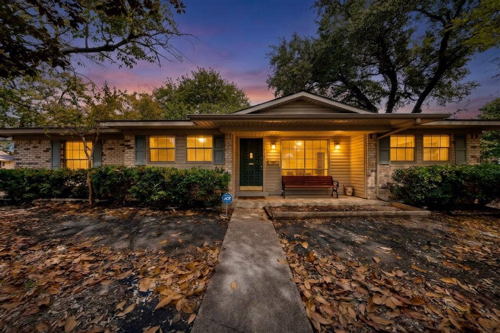 Brick and siding exterior with a covered entry, established landscaping, and a concrete pathway