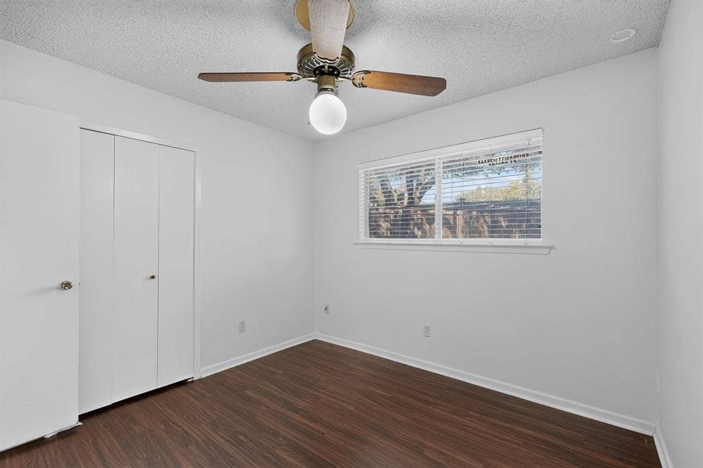 Wood-finish flooring, white walls, and a window with horizontal blinds