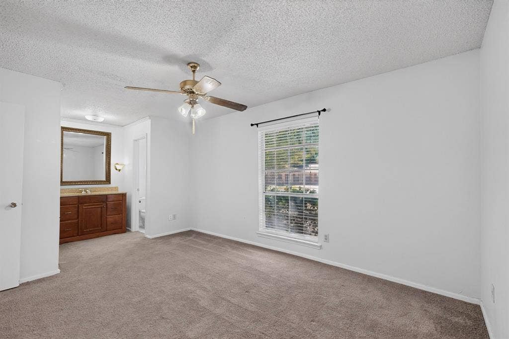 Wall-to-wall carpeting, window with blinds, ceiling fan, and an integrated vanity with a mirror