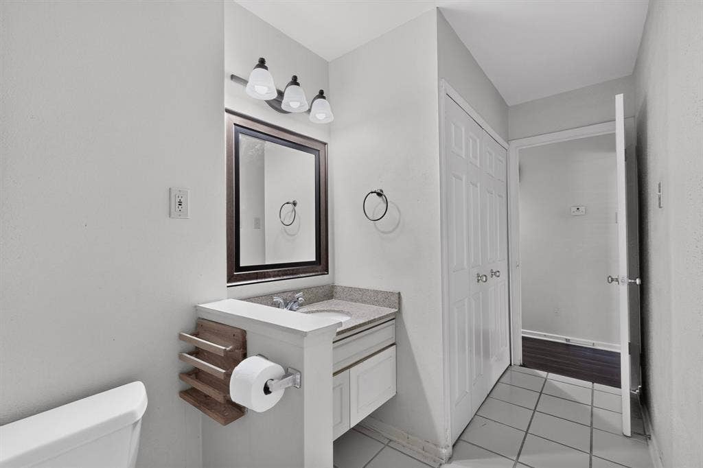Bathroom featuring a vanity with an integrated sink, framed mirror, and a three-light fixture