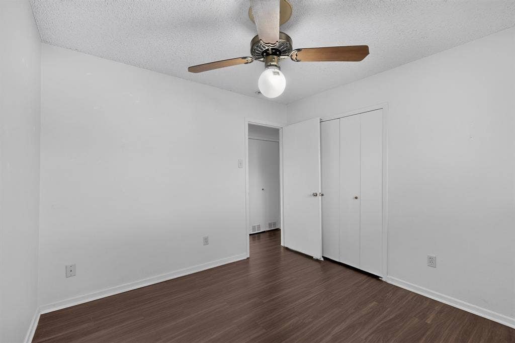 Wood-finish flooring, white walls, ceiling fan with light, and bi-fold closet doors