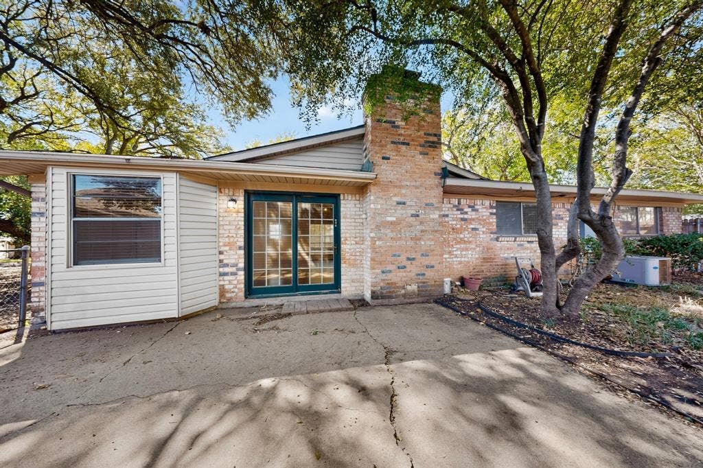 Brick exterior with a prominent chimney, double-pane sliding glass doors, and a covered patio area