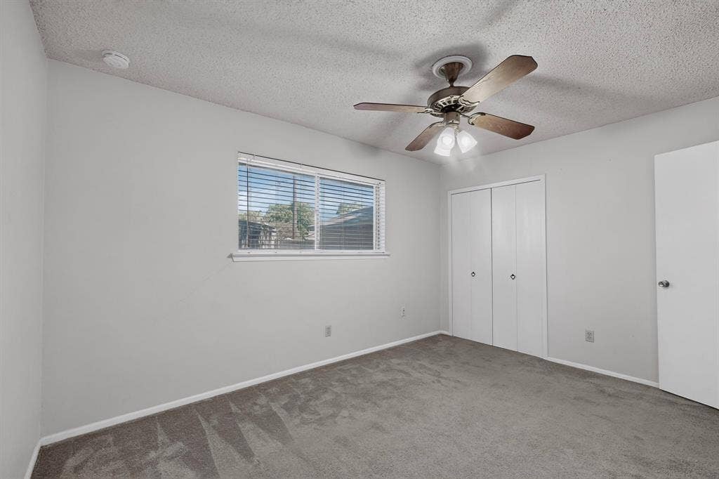 Wall-to-wall carpeting, window with blinds, ceiling fan with integrated lighting, and bi-fold closet doors