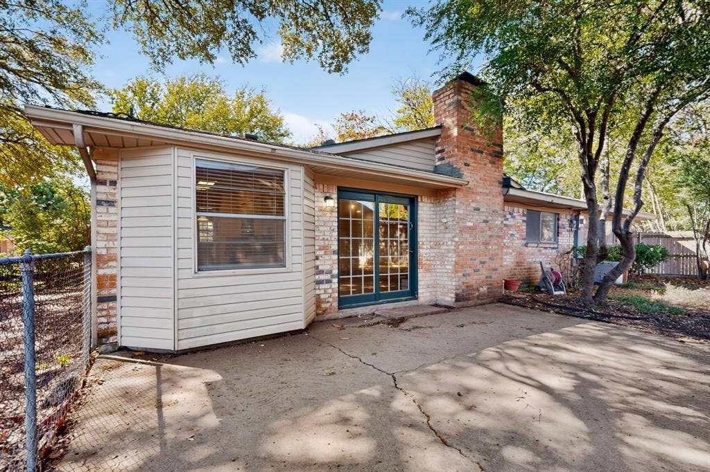 Rear exterior with brick and siding, featuring a prominent brick chimney, sliding glass doors, and a bay window