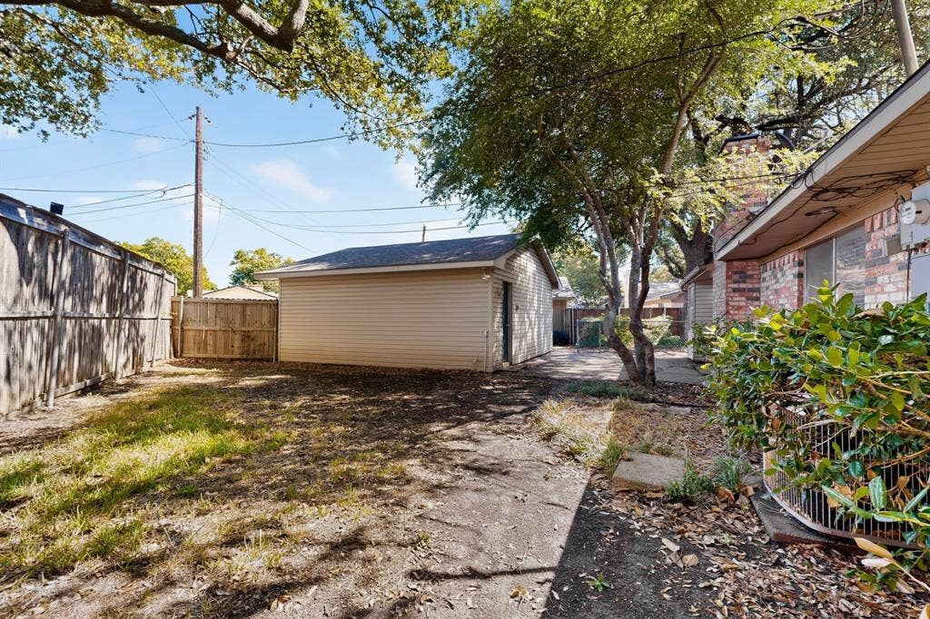 Expansive backyard featuring a detached structure with siding, mature trees, and a wooden privacy fence