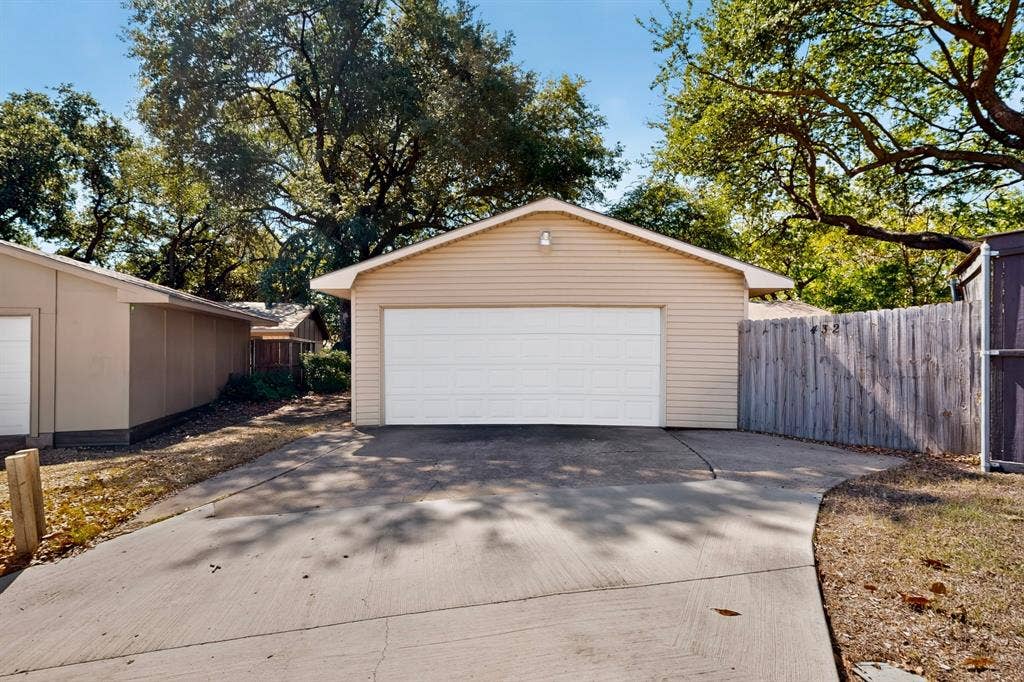 Detached garage with horizontal siding, a white garage door, and an exterior light fixture