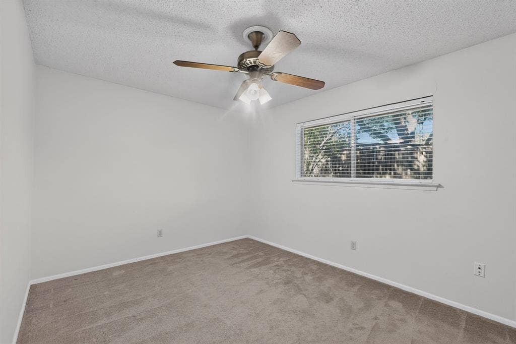 Recessed window with horizontal blinds, overhead ceiling fan with light fixture, textured ceiling, and carpeting