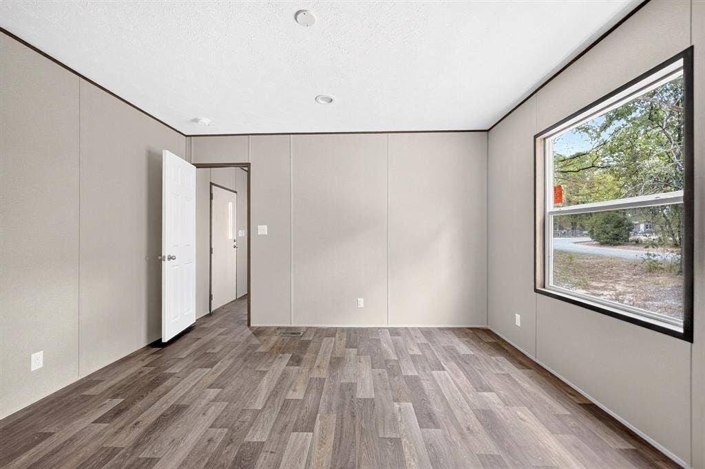 Neutral-toned walls with dark trim, wood-finish flooring, recessed ceiling lighting, and a dual-pane window