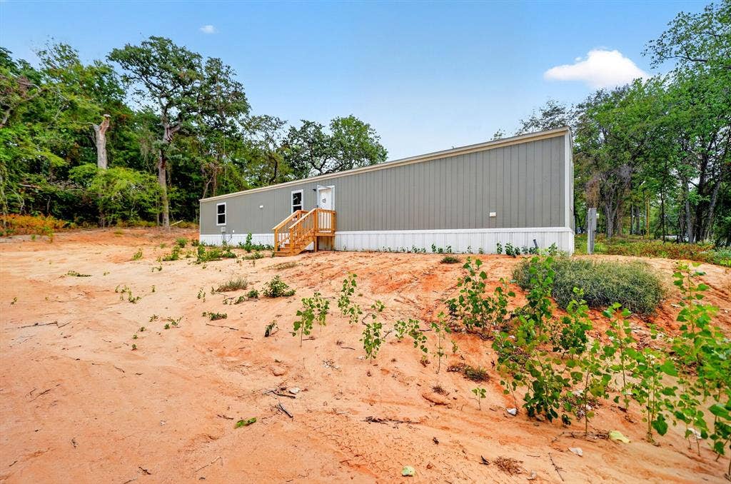 Single-level exterior featuring vertical siding, a shed-style roofline, and wood-framed stairs