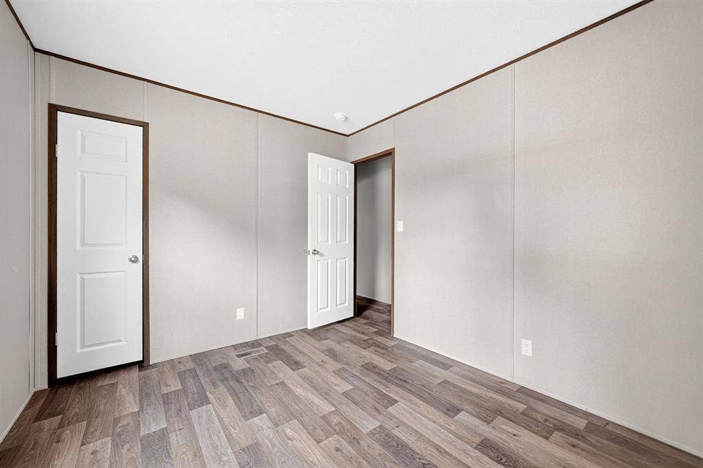 Interior space featuring wood-finish flooring, white six-panel doors, and neutral wall surfaces
