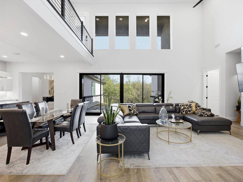 Living room featuring light wood-type flooring, a high ceiling, and recessed lighting