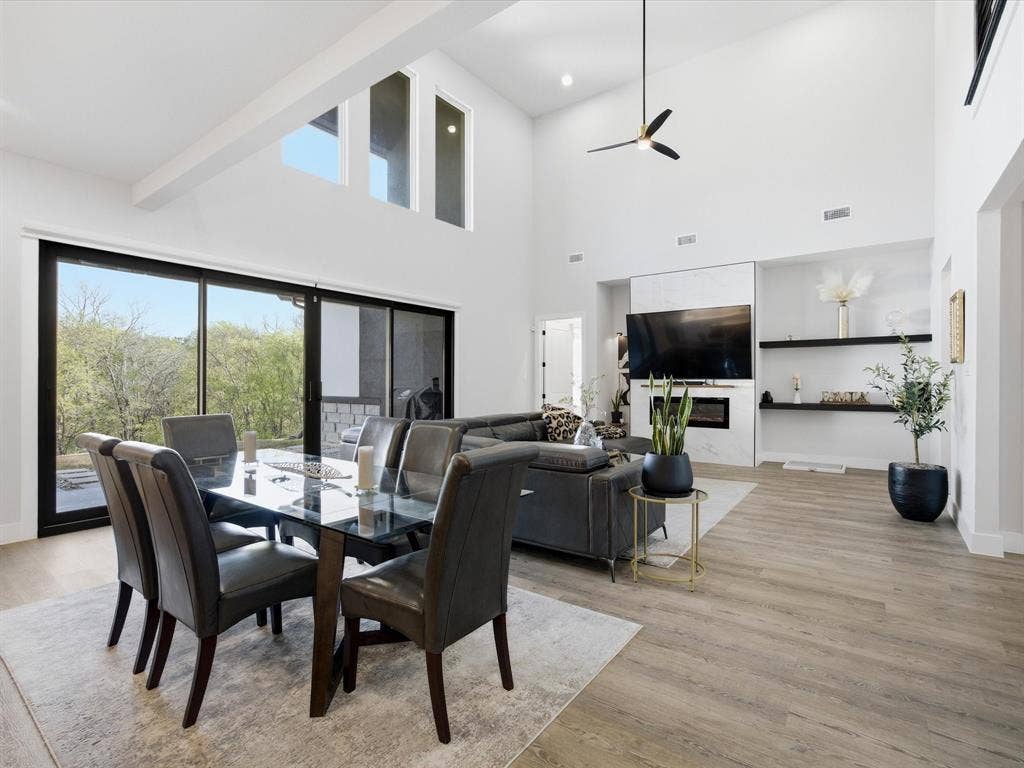 Dining area featuring light wood-style floors, a high ceiling, and ceiling fan