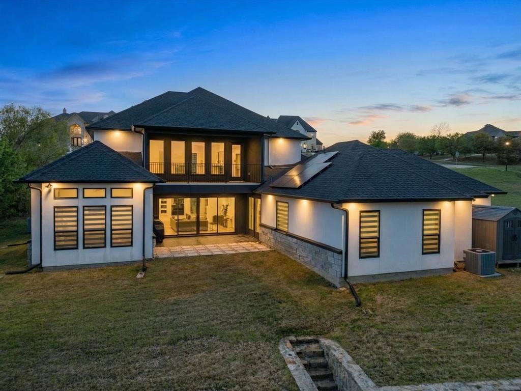 Back of house at dusk with a yard, stucco siding, and a patio area