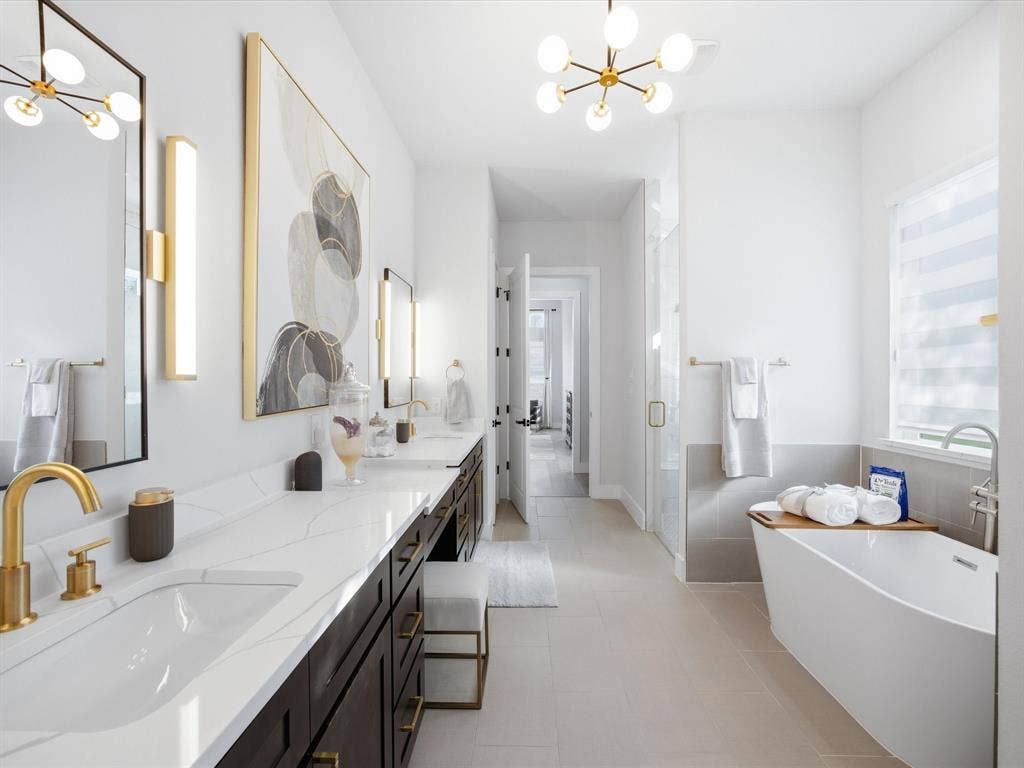 Bathroom featuring suspended lighting, a shower stall, a freestanding tub, and double vanity