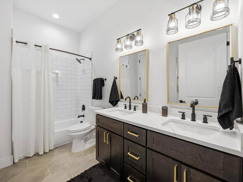 Bathroom featuring double vanity, light tile patterned floors, and shower / bath combo